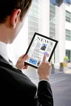 Businessman holding a touchpad pc, reading a newspaper