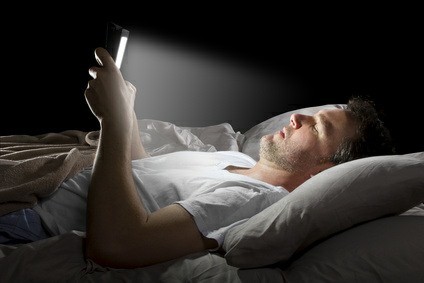 Man reading emails in bed