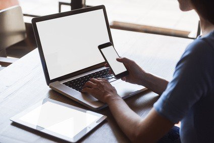 multitasking woman using tablet, laptop and cellphone, with blank screens, indoors on a table